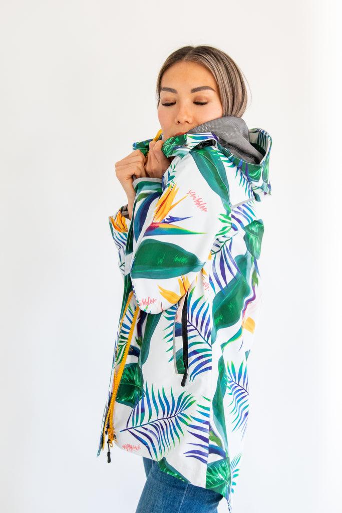 Scribbler rainwear, waterproof raincoat for women, rain jacket for ladies, outerwear, waterproof, mesh lined, lightweight, recycled plastic, sustainable fashion, winter coat, tropical Tropic print, mesh lined, beautiful, colourful print, breathable, packable coat, NZ, New Zealand designer, plus size, curvy, curves, white, green leaves, strelitzia, colourful rain jacket
