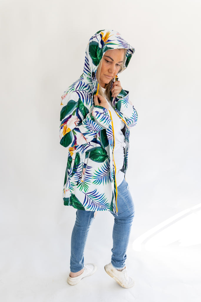 Scribbler rainwear, waterproof raincoat for women, rain jacket for ladies, outerwear, waterproof, mesh lined, lightweight, recycled plastic, sustainable fashion, winter coat, tropical Tropic print, mesh lined, beautiful, colourful print, breathable, packable coat, NZ, New Zealand designer, plus size, curvy, curves, white, green leaves, strelitzia, colourful rain jacket